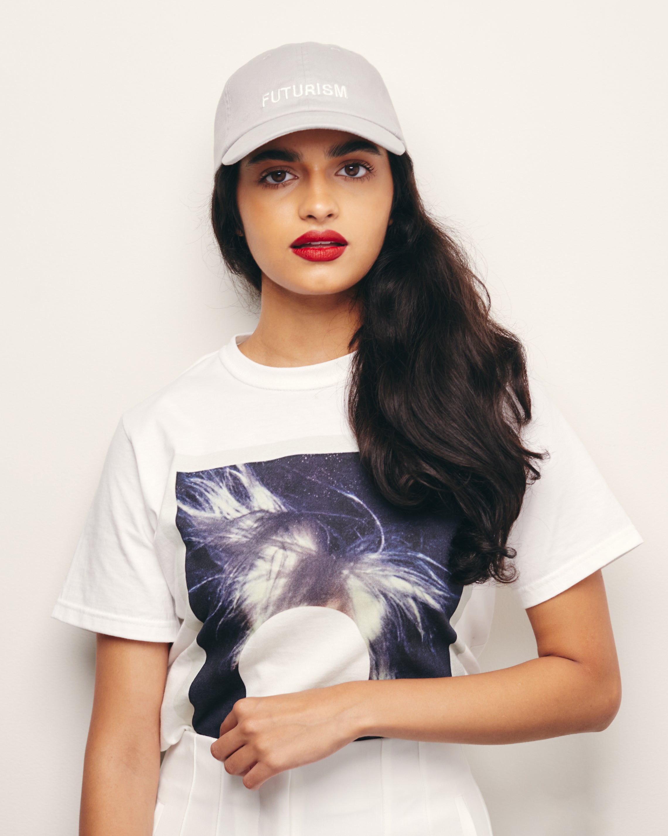 Mira Bhat wears Black / Charcoal Organic Short Sleeve 100% Cotton Tee with  graphic print of Andy Warhol’s Self Portrait Polaroid embellished with a John Baldessari white dot. 