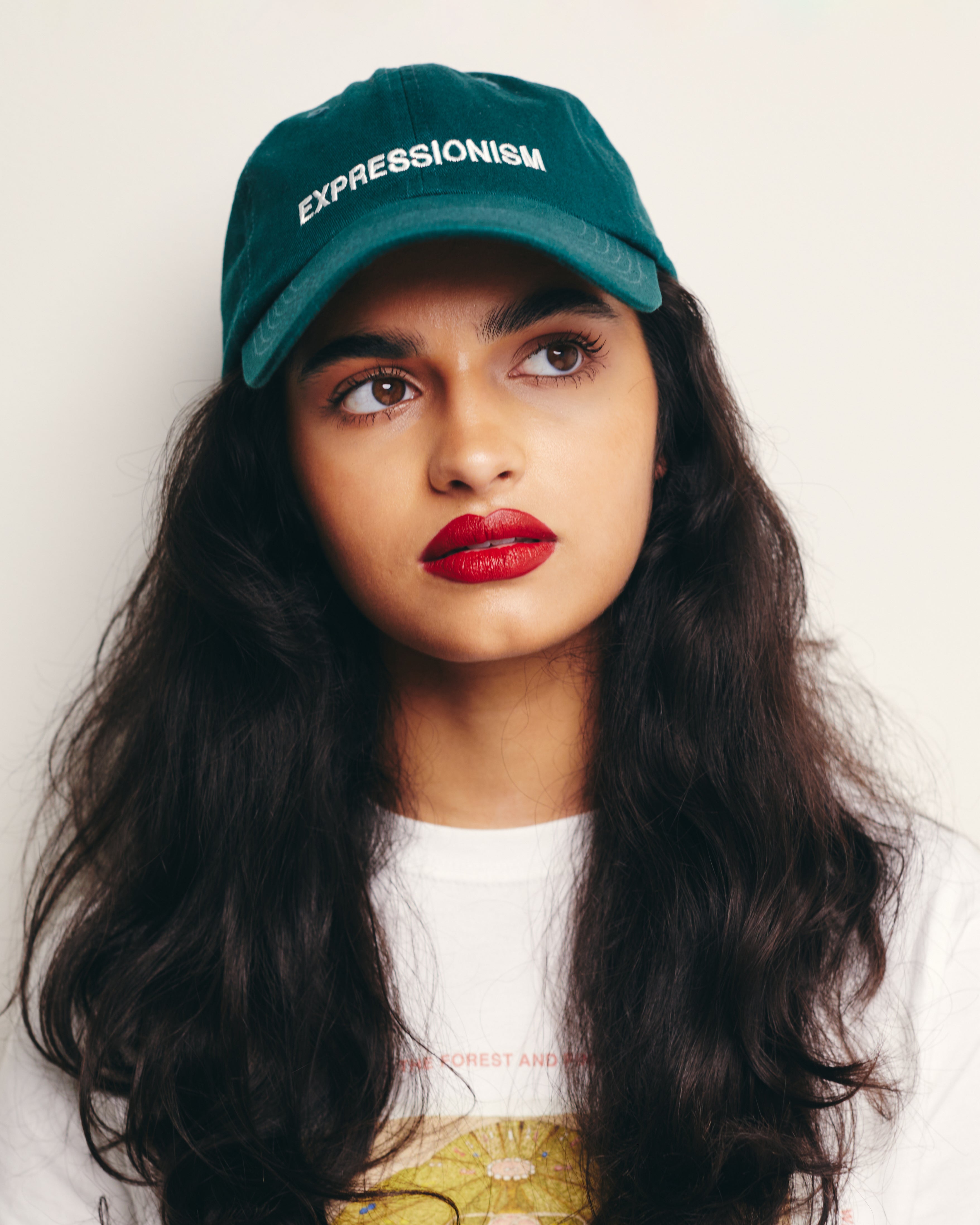Mira Bhat wears Green Baseball Cap / Dad Hat with Expressionism Art Movement Text Embroidery on Front. 100% Cotton.