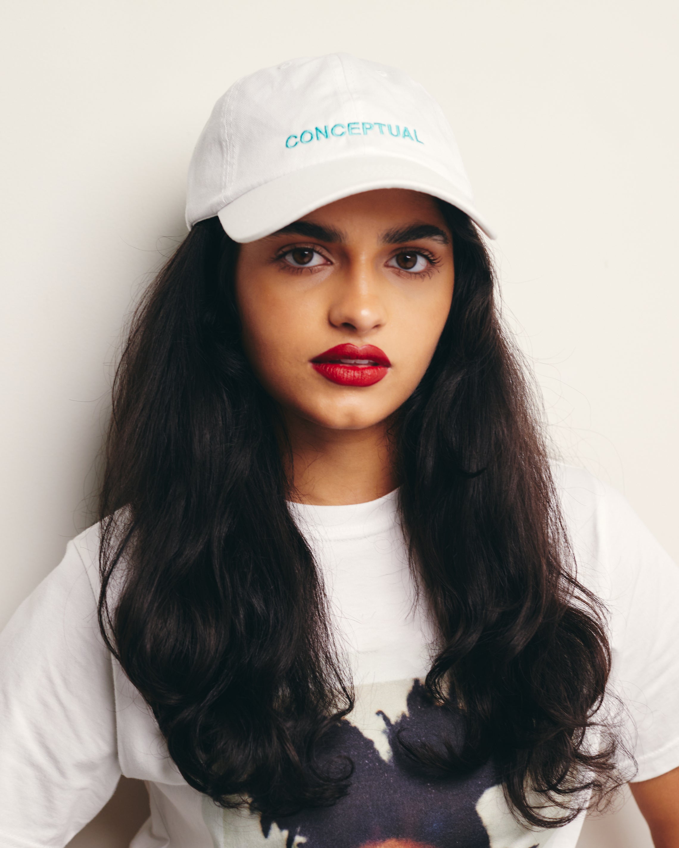 Mira Bhat wears White Baseball Cap / Dad Hat with Conceptual Art Movement Text Embroidery on Front. 100% Cotton.