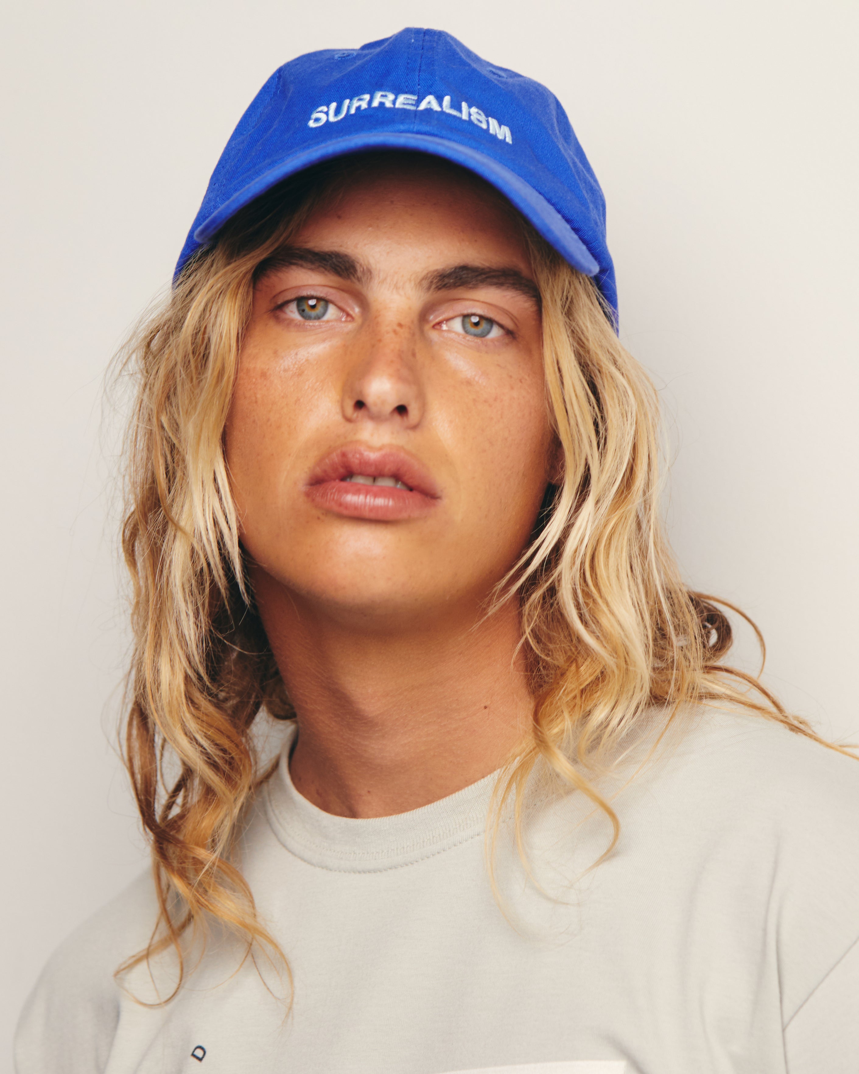 Lucas Ucedo Wears Royal Blue Dad Hat With Surrealism Embroidery Art Movement Text
