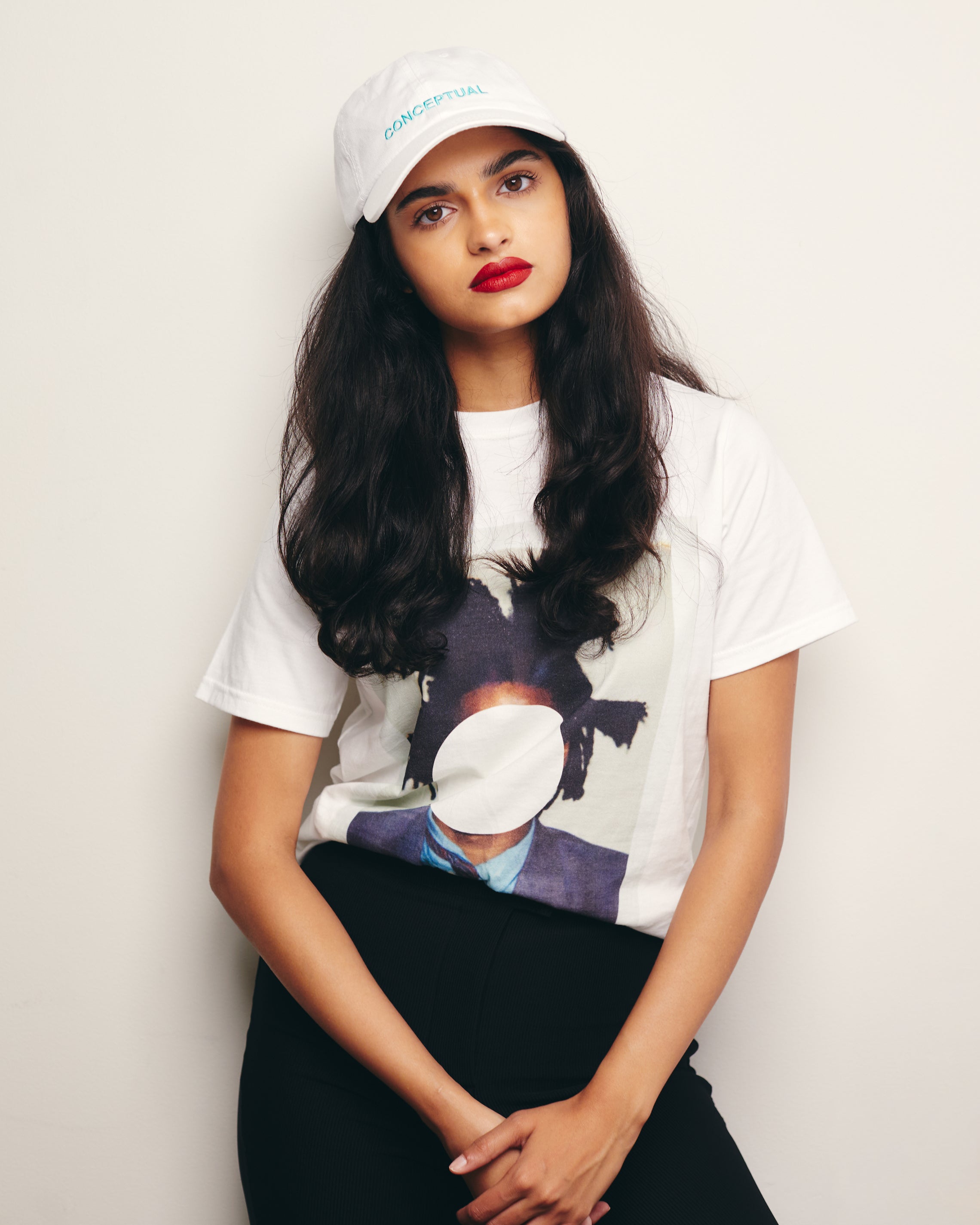 Mira Bhat wears White Organic Short Sleeve 100% Cotton Tee with  graphic print of Andy Warhol’s Portrait of Jean-Michel Basquiat Polaroid embellished with a John Baldessari white dot. 