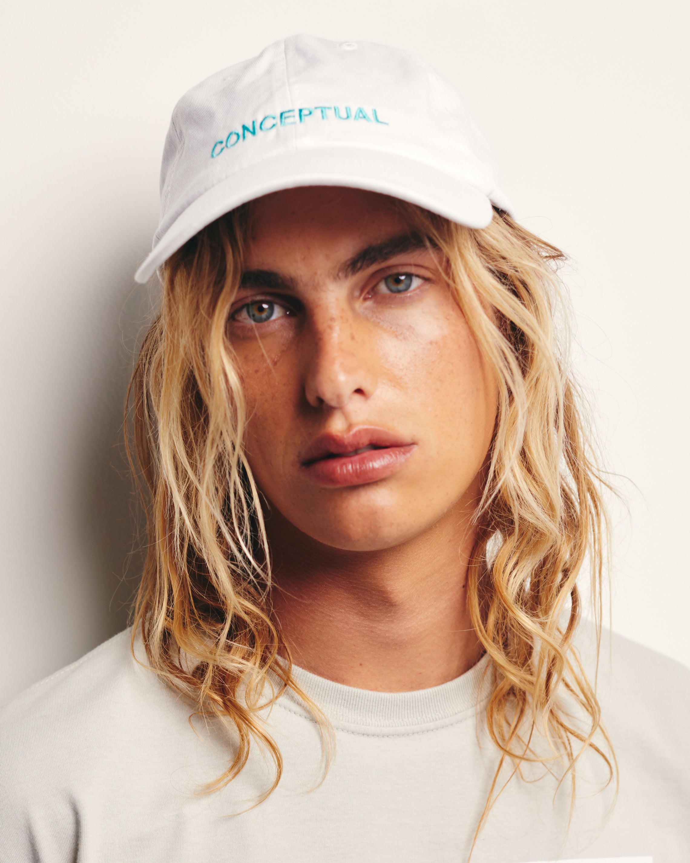 Lucas Ucedo wears White Baseball Cap / Dad Hat with Conceptual Art Movement Text Embroidery on Front. 100% Cotton.