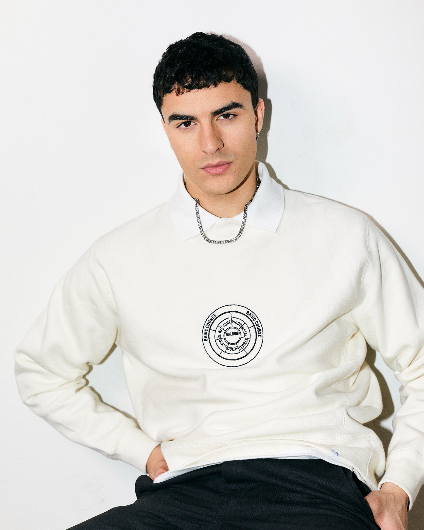 Arjang Mahdavi wears Cream / Off White / Ceramic Heavyweight Sweatshirt / Crewneck with embroidered print of the Bauhaus School Conceptual Curriculum Diagram and the Official Bauhaus seal on the back. 