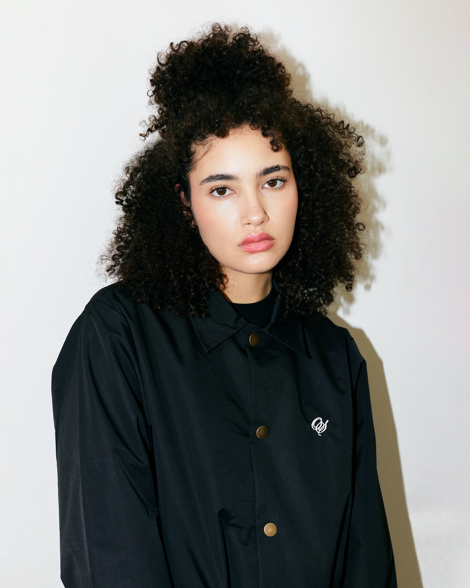 Teodora Marcella wears Black Mid-Weight Artist Smock Jacket with embroidered Outsider Supply Script. 100% Nylon. 